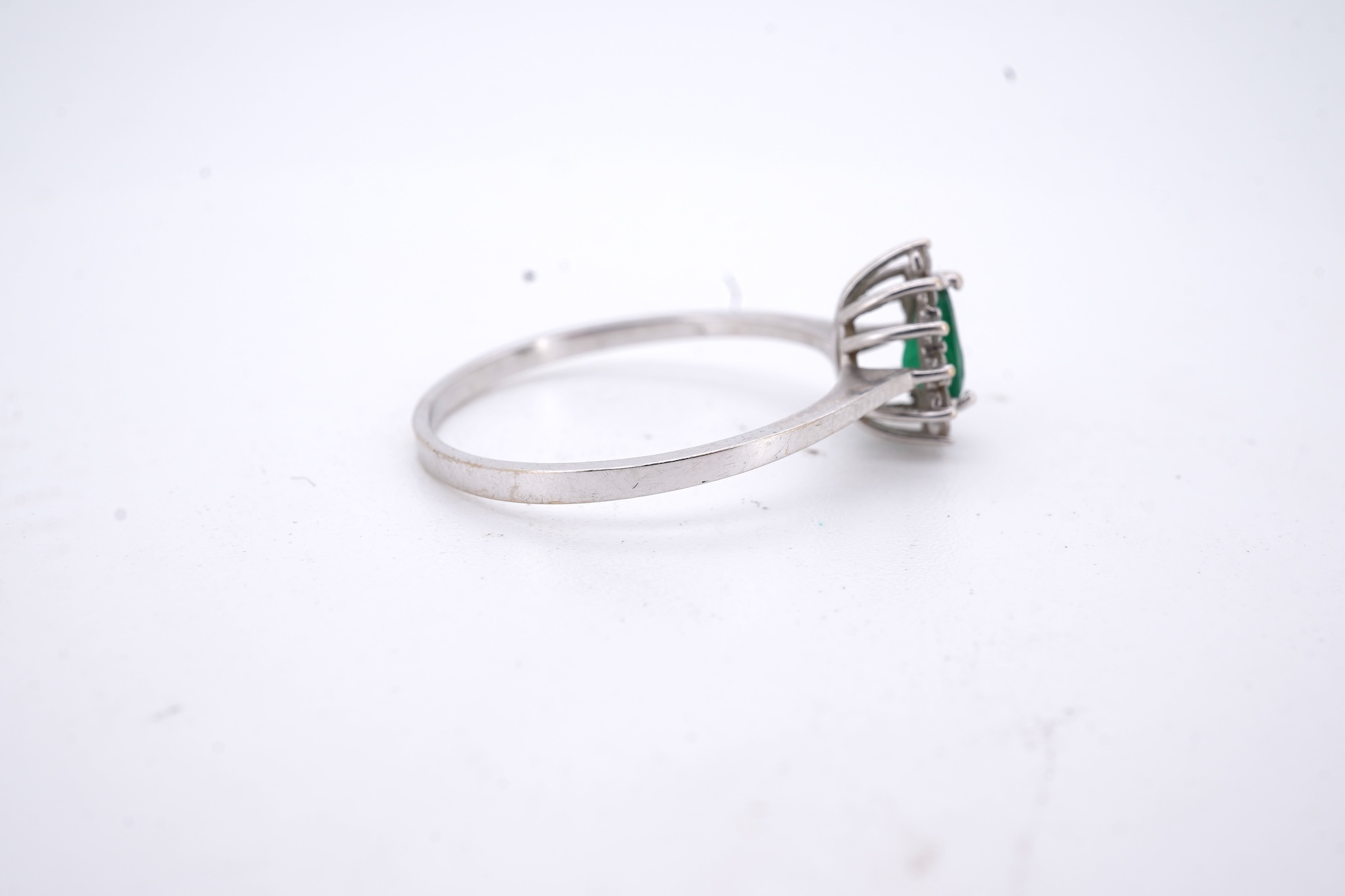 A modern white metal(stamped 14k), emerald and diamond set pear shaped cluster ring, size R, gross weight 1.3 grams.